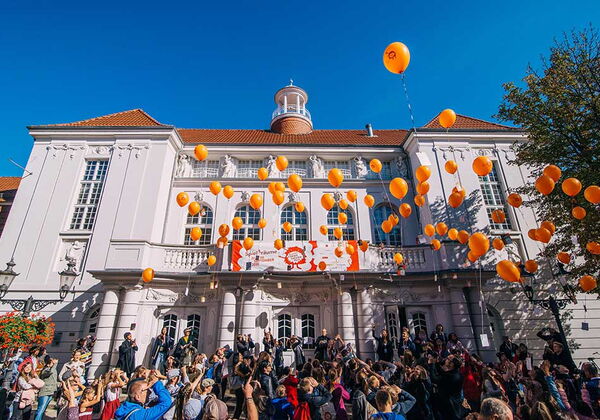 Viele Menschen stehen vor dem Stadttheater Minden und lassen orangene Ballons steigen